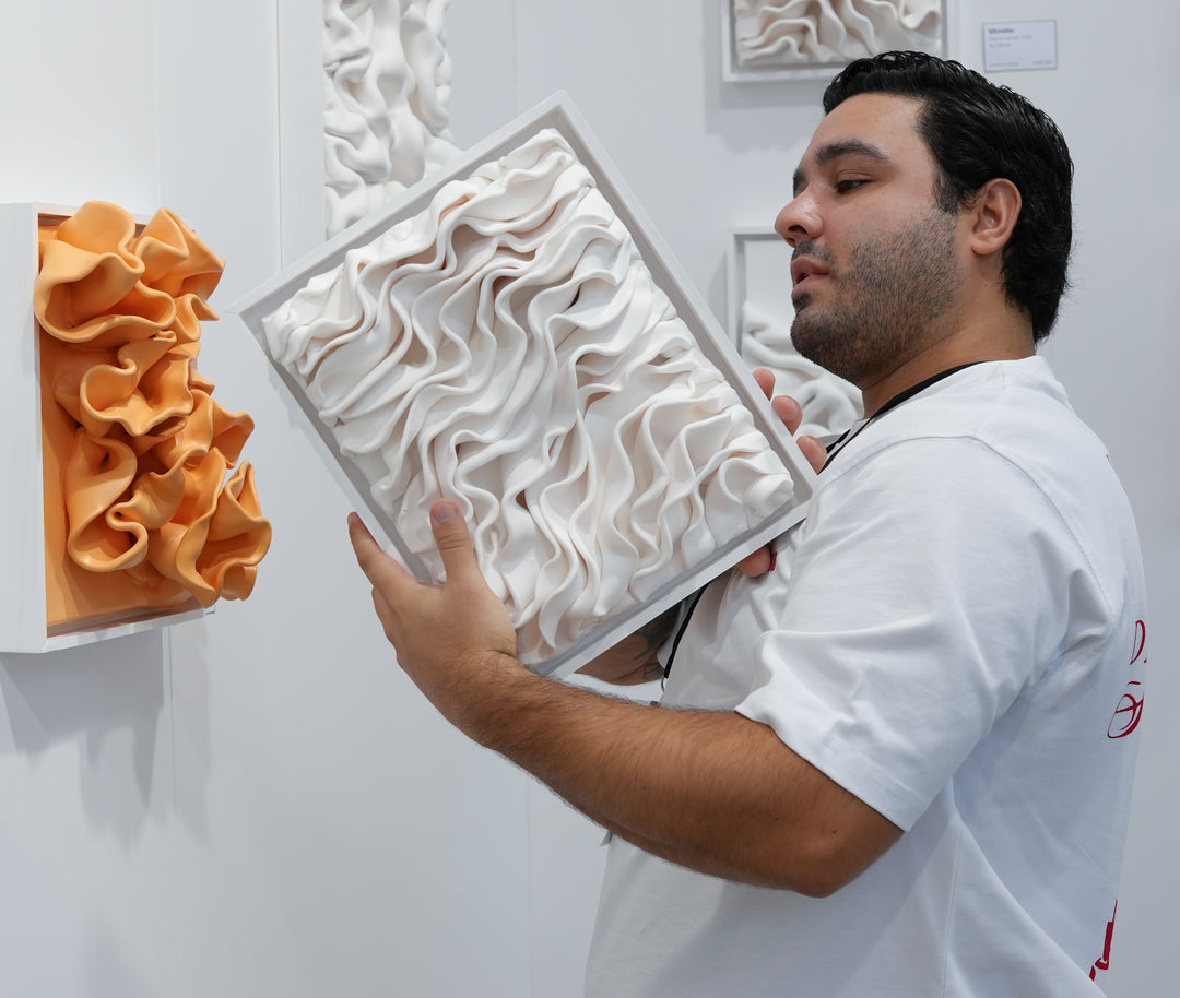 Daniel Pourrahmaty holding one of his sculptural clay wall artworks at Affordable Art Fair Stockholm.